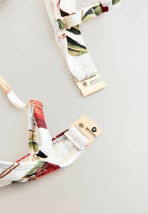 Blomstermønstrede justerbare stropper med guldfarvet metalbeslag og clips, med en hvid base og grønne og røde accenter.