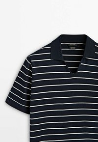 Polo bleu marine à manches courtes avec des rayures blanches horizontales et une ouverture de col en V.