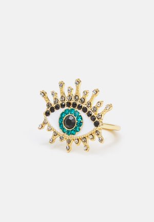 Gouden ring in de vorm van een oog, met een centrale zwarte steen omringd door turquoise en zwarte accenten, voorzien van kleine kristallen embellishments.