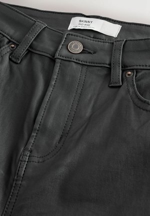 Jeans skinny a vita media in tessuto grigio scuro. Presentano tasche anteriori, hardware metallico e dettagli di cucitura a contrasto. Etichetta visibile.