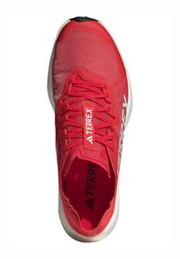 Scarpa atletica rossa con parte superiore in rete, lacci tonali, punta rinforzata e marchio bianco sui lati. Suola arrotondata per comfort e trazione.
