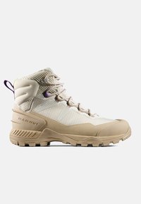 Beżowe buty trekkingowe z metalicznym wykończeniem, z gumową podeszwą, fioletowymi akcentami i wysokim kołnierzem dla wsparcia kostki. Związane sznurówkami.