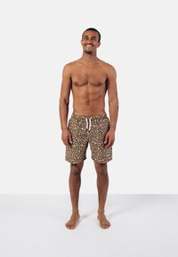Patterned swim shorts featuring yellow and orange dots on a black background, with a drawstring waist and side pockets.