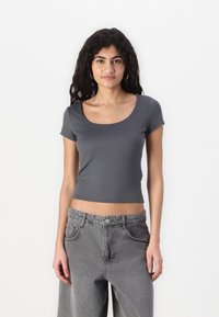 Crop top gris à manches courtes avec un col rond, fabriqué en tissu doux. Assorti à un pantalon en denim gris clair taille haute. Sans motifs.