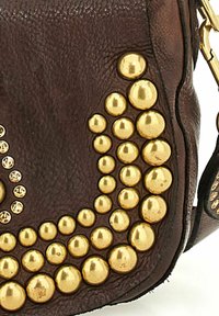 Borsa a mano in pelle marrone con un insieme di borchie dorate grandi e piccole disposte in un motivo curvato, con una superficie texture.