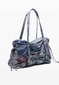 Štruktúrovaná kabelka z materiálu pripomínajúceho denim. Modré a sivé tóny s ornamentálnymi akcentmi. Má nastaviteľné remienky a kovové doplnky.