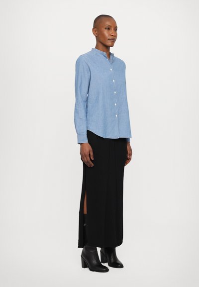 Lyseblå button-up skjorte med ståkrave, parret med en sort maxi-nederdel med sideskår og sorte hælede ankelstøvler.