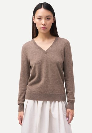 Brauner, weicher Wollpullover mit V-Ausschnitt, langen Ärmeln und gerippten Bündchen. Hat eine lockere Passform und eine glatte Textur, kombiniert mit einem weißen Rock.