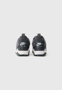 Ténis Nike Air com um upper cinza escuro, textura em malha, colarinho acolchoado e entressola branca com marca na parte de trás e nos lados.