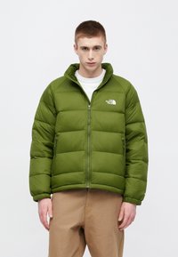 Zaļa pūkaina virsjaka ar rāvējslēdzēja aizdari, šuvju detaļām un logotipu uz krūtīm. Aprīkota ar elastīgām aprocēm un augstu apkakli siltumam.