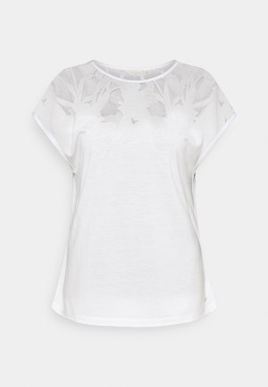 Blusa blanca de manga corta con cuello redondo y detalle de encaje floral transparente en los hombros y parte superior del pecho.