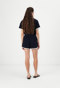 Navy knit matching set featuring a short-sleeve top and shorts with white lace trim. The fabric has a textured, open weave.