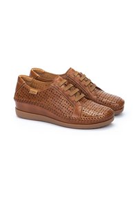 Zapatillas de piel marrón con un patrón floral cortado a láser, suelas planas y cordones a juego. Presentan costuras decorativas a lo largo de los bordes.