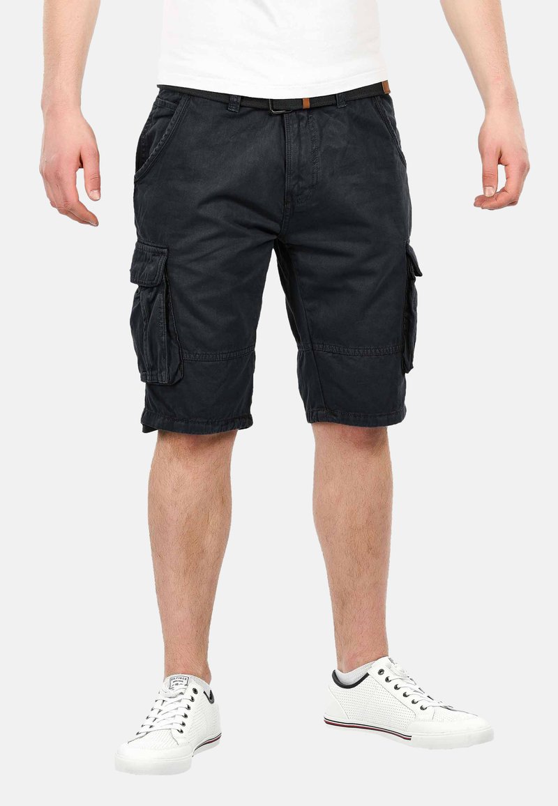 Black cargo shorts made from cotton, featuring side pockets and a relaxed fit. Paired with white sneakers with a textured finish.