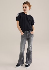 Mornarsko plavi kratki rukav s teksturom i uzorcima, uparen s sivim trapericama širom nogavicom i crnim tenisicama. Jednostavan dizajn, opušteni kroj.