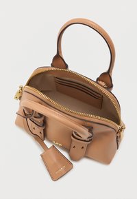 Μικρή καφέ δερμάτινη τσάντα με διπλά χερούλια, ανοιχτό χρυσό φερμουάρ που αποκαλύπτει τον άδειο εσωτερικό χώρο με θήκες για κάρτες και ετικέτα δερμάτινη με λογότυπο προσαρτημένη.