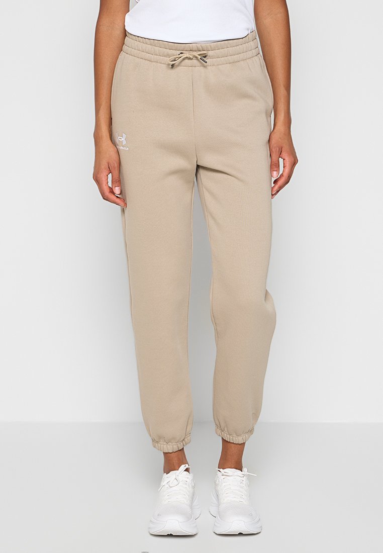 Pantalons de jogging beiges avec taille à cordon et poignets élastiques, portés avec des baskets blanches et un haut blanc, vue de face.