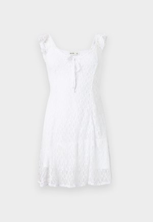 White sleeveless lace dress with ruffled shoulder straps, fitted bodice, front tie detail, and flared skirt, displayed on plain background.