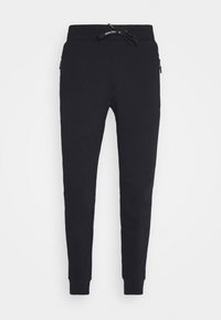 Joggers de algodón negro con cintura elástica y cordón, piernas ajustadas y bolsillos laterales con cremallera. Textura suave; diseño minimalista.