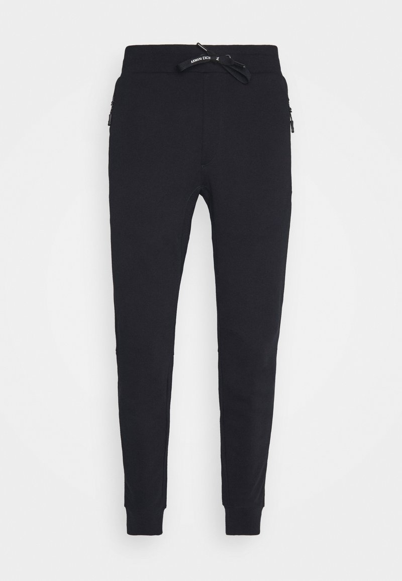 Joggers de algodón negro con cintura elástica y cordón, piernas ajustadas y bolsillos laterales con cremallera. Textura suave; diseño minimalista.