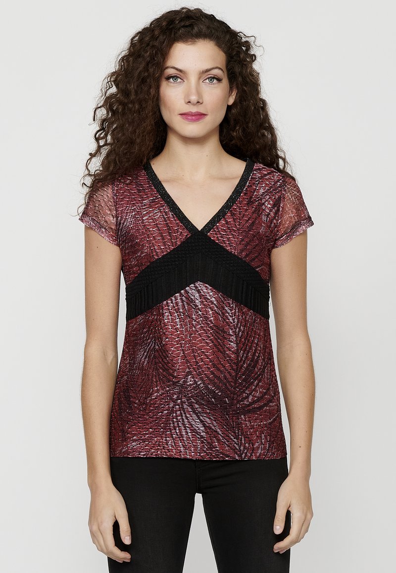 Top corto rosso e nero a manica corta con scollatura a V, motivo testurizzato e dettagli neri sul décolleté. Tessuto liscio con un design aderente.