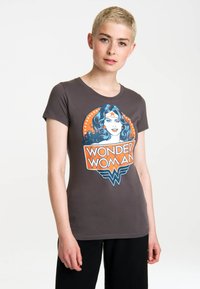 Dark gray t-shirt featuring a colorful Wonder Woman graphic with a round emblem, stars, and bold lettering; short sleeves and fitted design.