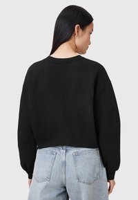 Sudadera corta negra con mangas largas y abullonadas, y un cuello redondo, que presenta una textura suave y detalles de costura mínimos.