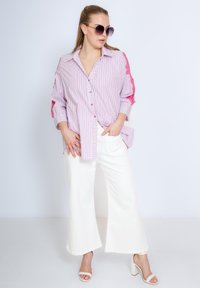 Roze en witte gestreepte blouse met kantaccenten op de mouwen, gecombineerd met witte wijde broek en witte hakken.