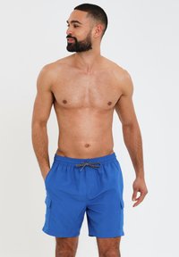 Shorts de bain bleus pour hommes en tissu léger, dotés d'une taille élastique avec cordon de serrage et de poches latérales. Design simple et fonctionnel.