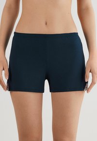 Mörkblå shorts av mjukt tyg med elastisk midja och spetsdetaljer på sidorna, med en figursydd, rak design.