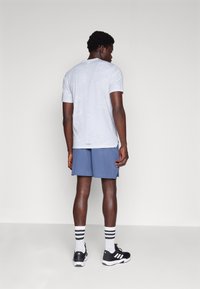 Light grey short-sleeve shirt, blue shorts, black athletic shoes with white accents, and white socks featuring black stripes.