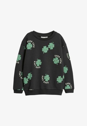 Zwarte sweatshirt met groene, glimlachende klavertjes vier en de tekst "Good Luck" verspreid over de voorkant en mouwen.