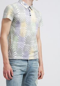 Chemise polo imprimée ananas aux couleurs pastel, dotée d'un col étalé, d'une patte de boutonnage à trois boutons et de manches courtes. Tissu doux et léger.