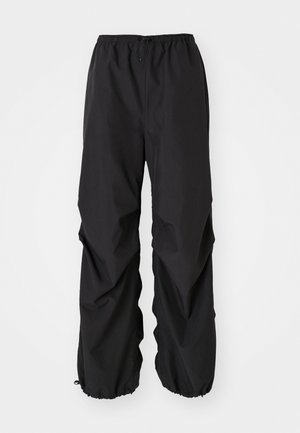 Fekete, vízálló anyagból készült, rugalmas derékpántos nadrág. Laza szabása van, az alsó részen összehúzott mandzsettákkal, látható minták nélkül.