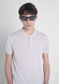 Polo shirt corto beige chiaro con colletto e tre bottoni, dotato di un tessuto testurizzato. Occhiali da sole neri rettangolari indossati.