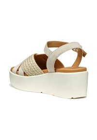 I sandali intrecciati beige presentano una suola piattaforma, un design con fasce incrociate e una cinghia posteriore regolabile. Il materiale testurizzato combina suede e dettagli intrecciati.
