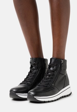 Zwarte leren sneakers met hoge schacht, veters en ritssluiting. Voorzien van een witte accentstreep op de zool en een gestructureerd oppervlak.