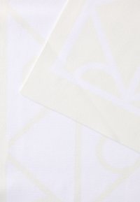 Pamut textil, amelyen világos, geometrikus minta látható finom fehér árnyalatokban, texturált felülettel és sima felülettel, rétegezett, átfedő darabokkal.