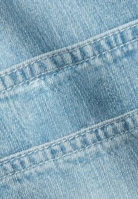 Ljusblå denimtyg med en lätt strukturerad yta. Har sydda sömmar och subtila färgvariationer f ör en sliten look.