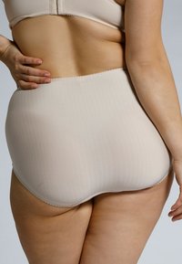 Beige high-waisted ondergoed van gladde stof met een streeppatroon en gegolfde randen, getoond vanuit een zijperspectief.