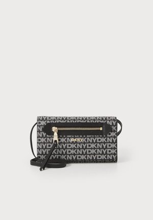 Black and white bag featuring repeating "DKNY" logo, horizontal zip pocket, gold-tone zipper hardware, textured fabric, and removable shoulder strap.