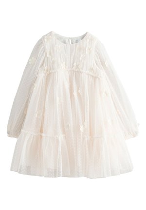 Kerma-värinen pitkähihainen taaperomekko, jossa läpikuultava pilkullinen kangas, kukkakoristeet, kerätty vyötärö ja röyhelöhelma.