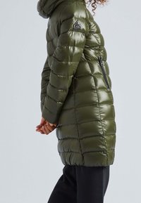 Olivově zelený prošívaný péřový kabát s kapucí, se zapínáním na zip, bočními kapsami a logem na rukávu.