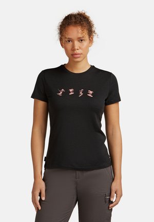 T-shirt nera a maniche corte realizzata in morbido tessuto, caratterizzata da quattro grafiche rosa di sciatori sul petto. Collo rotondo classico.