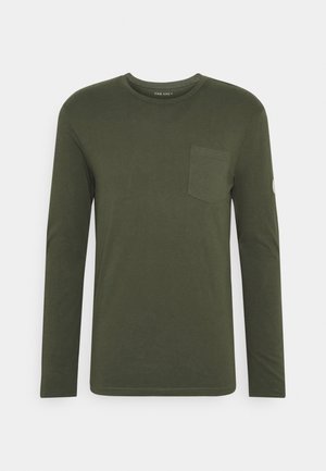 Camisa de manga larga de cuello redondo en verde oliva con bolsillo en el pecho y pequeño parche redondo de logo en la manga izquierda.