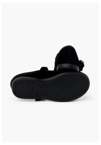 Zapatos de ante negro con tacón bajo, que presentan una correa con una hebilla decorativa, suela de goma texturizada para mayor agarre y diseño de punta redondeada.