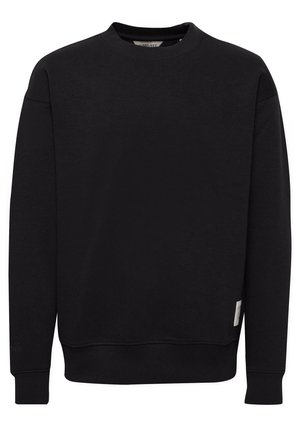Svart crewneck sweatshirt laget av mykt stoff, med ribbede mansjetter og hem, samt et lite merke på siden nær bunnen.