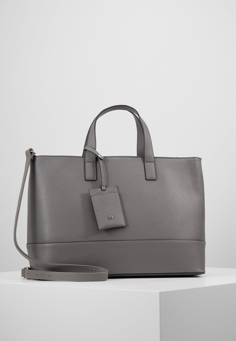 Bolso tote sintético gris con asas dobles, correa para el hombro desmontable, superficie texturizada y una etiqueta de equipaje a juego con logo en relieve.