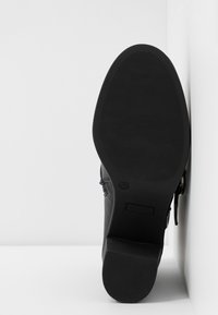 Mustat nilkkurit, joissa on teksturoitu kumipohja, matala korko ja sivuvetoketjuyksityiskohta. Suuri nahkainen päällinen hienovaraisilla ompeluyksityiskohdilla. Koko 36.