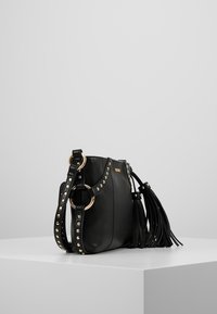 Borsa in pelle nera con un design morbido, dettagli in metallo dorato, tracolla borchiata e frange su un lato. Compatta e con finitura texture.